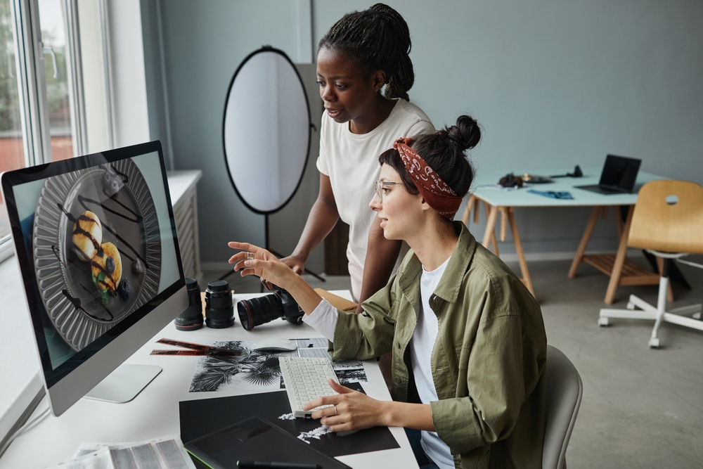 Side,View,Portrait,Of,Two,Female,Photographers,Discussing,Images,On